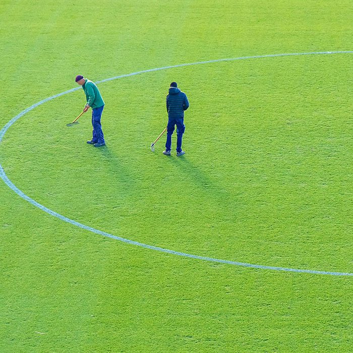 Two Guys Work on a Sports Field